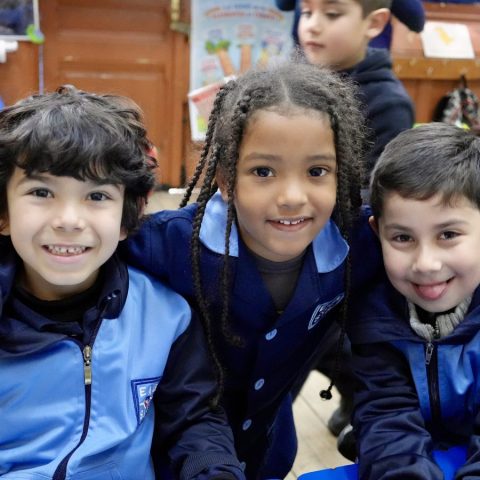 Tres estudiantes de los primeros niveles abrazados en la sala