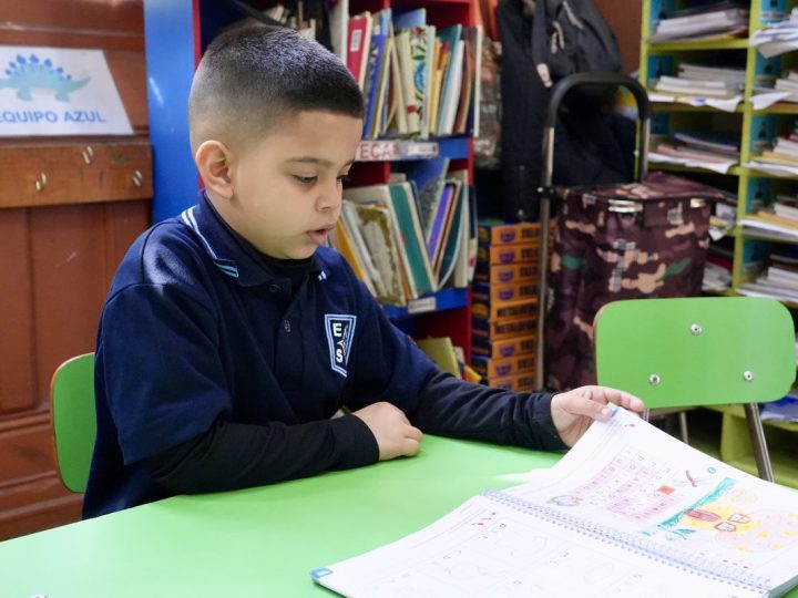 Estudiante leyendo un libro ilustrado en la biblioteca