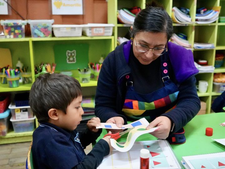 Estudiante y educadora trabajando con papeles de colores en el taller