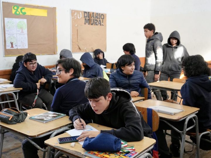 Estudiantes escribiendo en la sala, junto al diario mural del curso