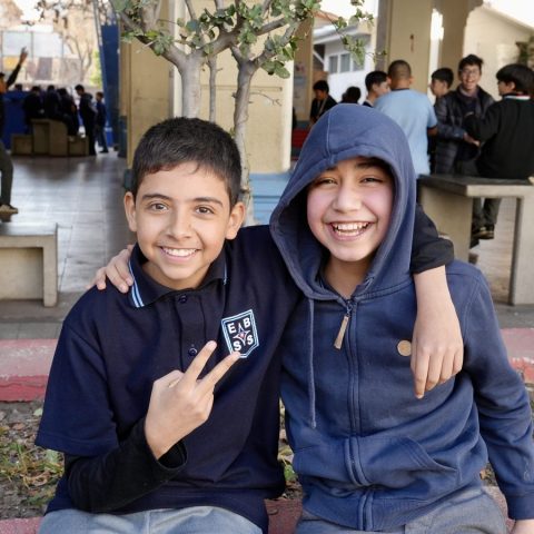 Dos estudiantes abrazados en el patio de la escuela