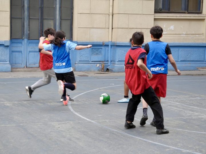 Estudiantes disputando el balón durante un partido de fútbol en la cancha