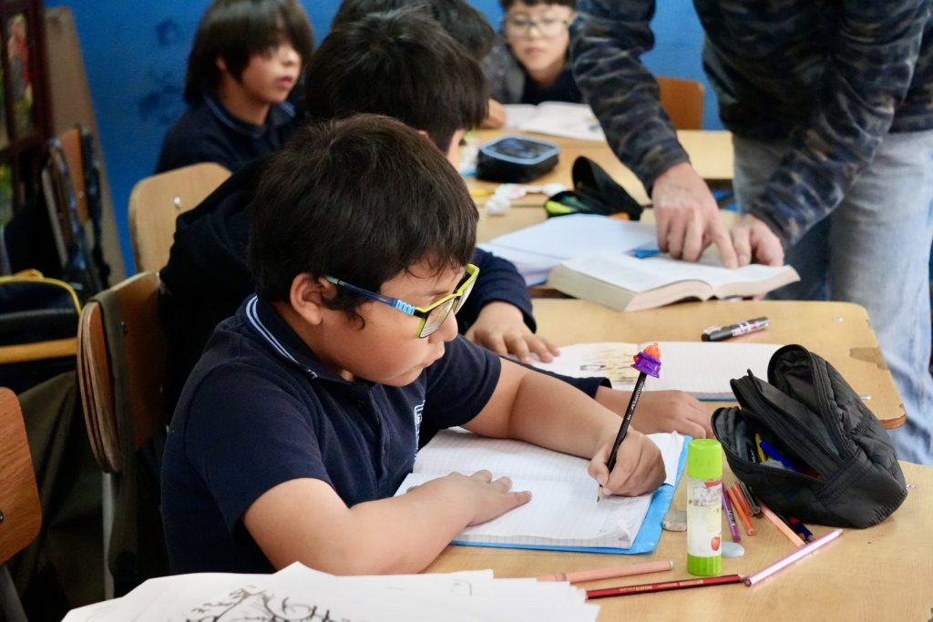 Estudiante trabajando en su cuaderno junto a sus compañeros
