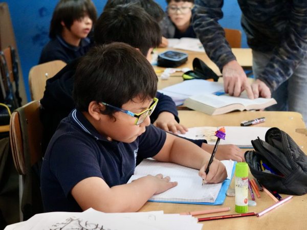 Estudiante trabajando en su cuaderno junto a sus compañeros