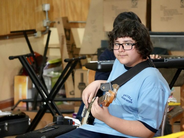 Estudiante tocando la guitarra eléctrica en la sala de música