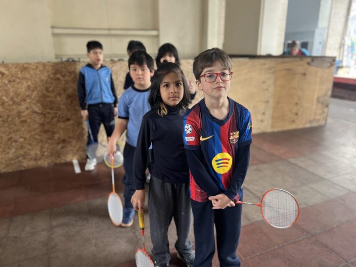 Estudiantes con raquetas de bádminton en el patio techado
