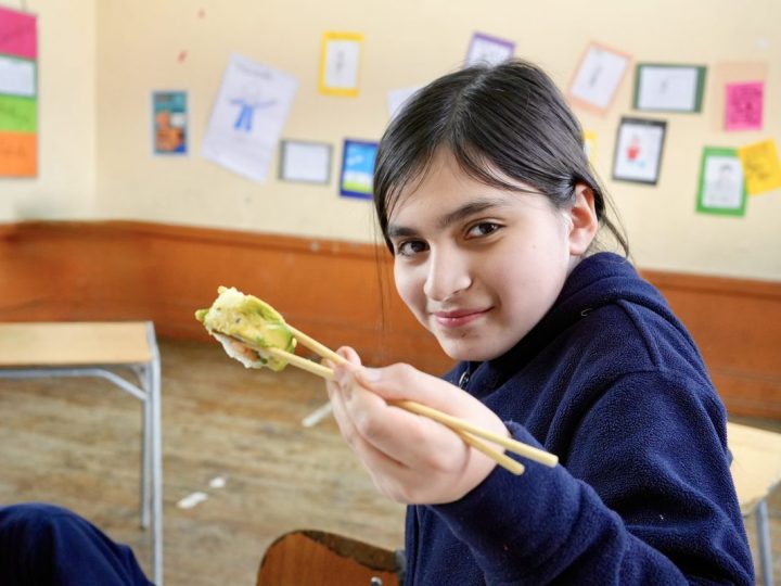 Estudiante sosteniendo con palillos una preparación del taller de japonés